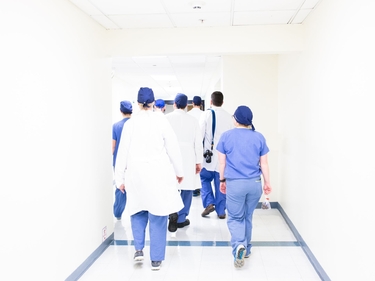 Medizinisches Fachpersonal läuft einen hellen Krankenhausflur entlang