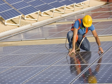 Ein Arbeiter legt Solarpanele auf ein Dach