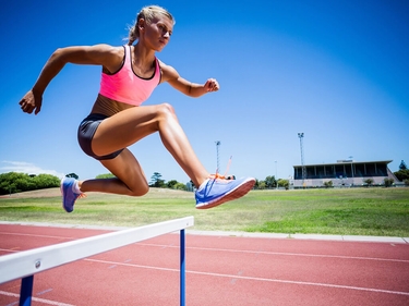 Sportlerin springt über eine Hürde