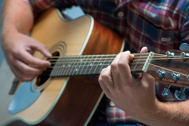 ein Musiker spielt auf einer akustischen Gitarre