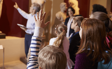 eine Mann zeigt einer Gruppe von Kindern Ausstellungsstücke in einem Museum