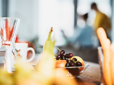 Obstkorb im Büro, dahinter Menschen