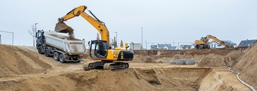 Ein Bagger hebt Sand aus einer Grube in einen LKW