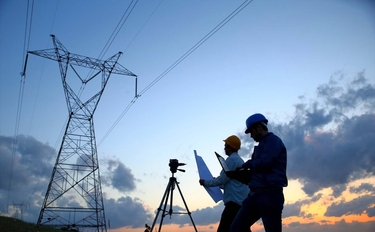 zwei Ingenieure arbeiten bei Sonnenuntergang vor einem Elektrizitätswerk