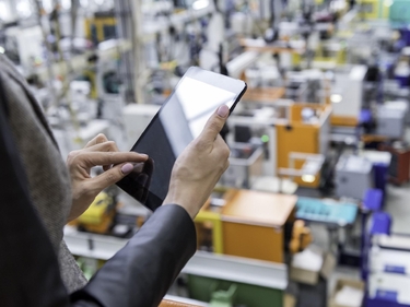 Mensch arbeitet an einem Tablet in einer Fabrikhalle
