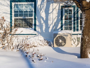 Wärmepumpe vor einem Wohnhaus im Schnee