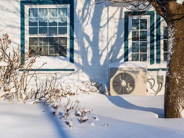 Wärmepumpe vor einem Wohnhaus im Schnee