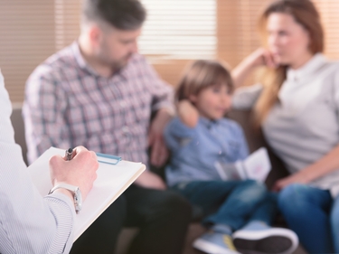 Familie sitzt auf einem Sofa und lässt sich beraten