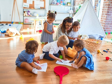 Eine Frau spielt mit mehreren Kindern in einer Kindertagesstätte