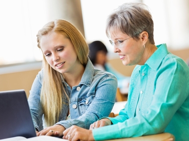 Seniorin, die eine Jugendliche beim Lernen unterstützt