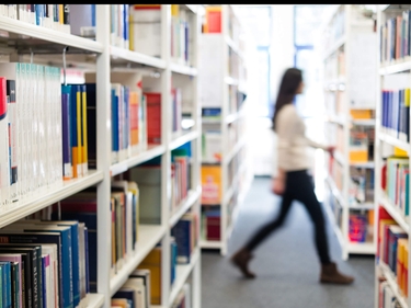 JUnge Frau läuft durch eine Bibliothek