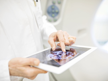 Tablet mit Röntgenbild, das von einer Person in einem weißen Kittel in den Händen gehalten wird