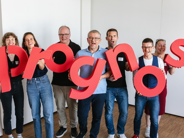 Kolleginnen und Kollegen halten die Buchstaben des Prognos-Logos