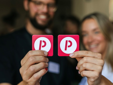 Zwei Personen zeigen ein Kartenspiel mit dem Prognos-Logo