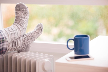 Ein Paar Füße in dicken Wollsocken liegen auf einer Heizung.