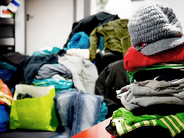 Aufgetürmte Kleiderspenden im Büro