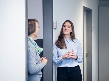 Zwei Frauen stehen ins Gespräch vertieft im Türrahmen