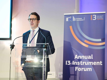 Dr. Jan-Philipp Kramer spricht am Rednerpult vor Banner des I3 Instrument Forum.