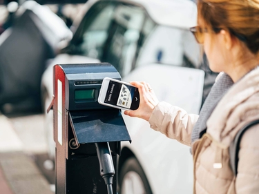 Frau zahlt kontaktlos für das Laden eines Elektroautos