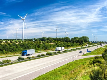 Verkehr auf der Autobahn, im Hintergrund Windkraftanlagen