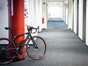Schwarzes Sportrad lehnt an roter Säule im Berliner Prognos-Büro