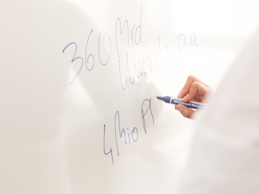 Ein Mann schreibt Umsatzzahlen auf ein Whiteboard