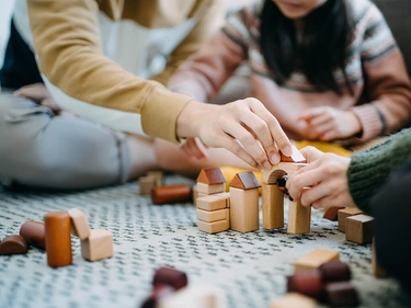 Eine Familie baut Häuser aus Bauklötzen