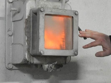 Eine Hand betätigt den Hebel einer thermischen Abfallbehandlungsanlage