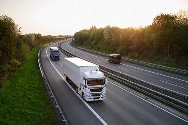 zwei LKWs und ein Auto fahren auf einer Autobahn