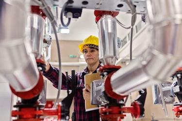Eine Ingenieurin begutachtet einen Industrieroboter bei der Arbeit