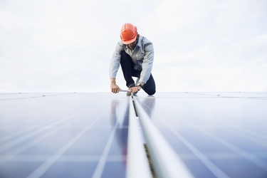 Ein Mann trägt einen Schutzhelm und arbeitet an Solarpanelen