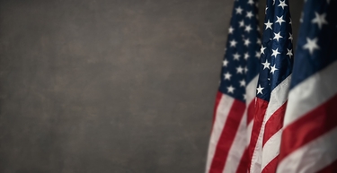eine US-amerikanische Flagge vor einem grauen Hintergrund