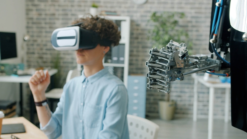 Frau mit VR-Brille und Roboter bewegen simultan die Hände