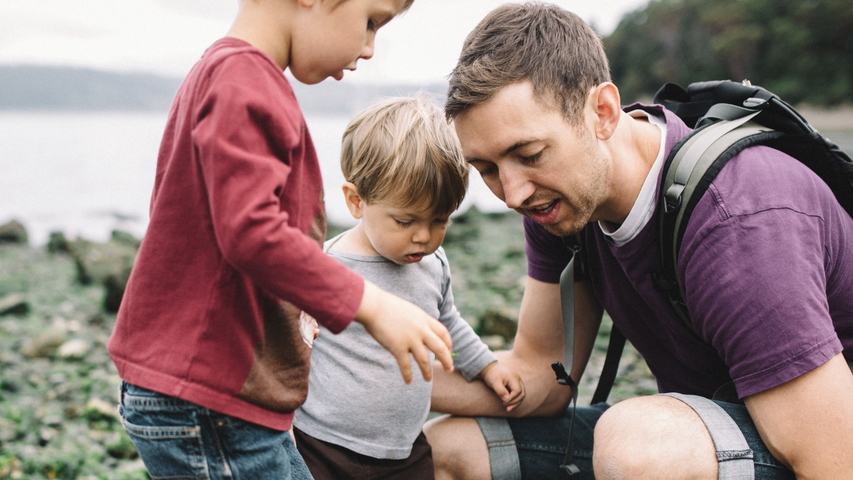 Vater spielt mit Kindern an einem See