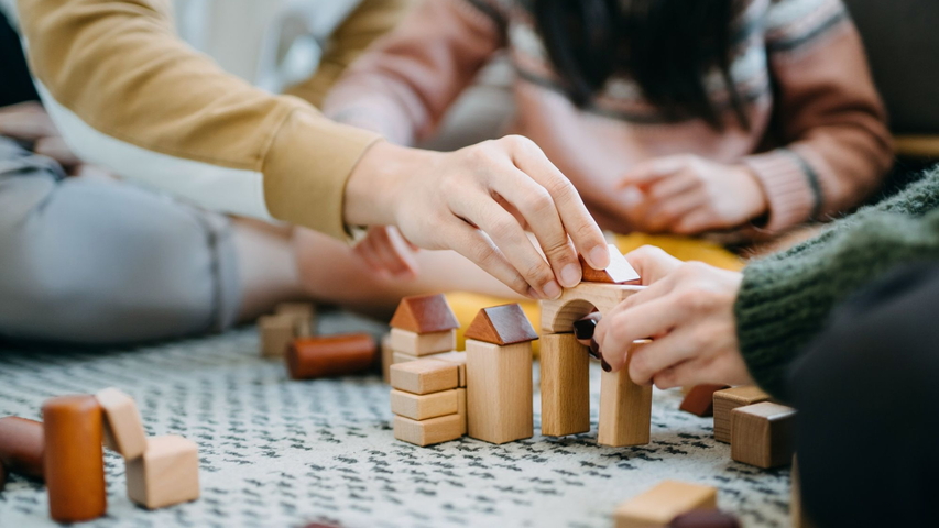 Kinder spielen mit Holzspielzeug und bauen ein Haus