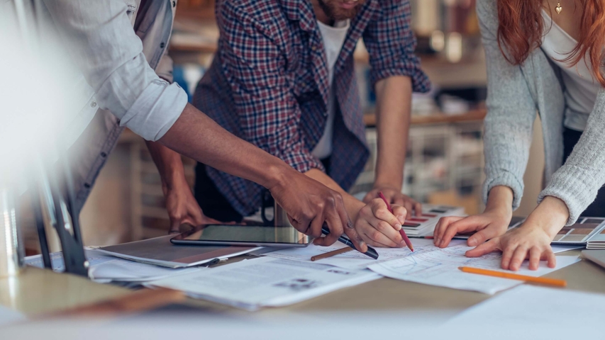 drei junge Architekten arbeiten gemeinsam an Zeichnungen