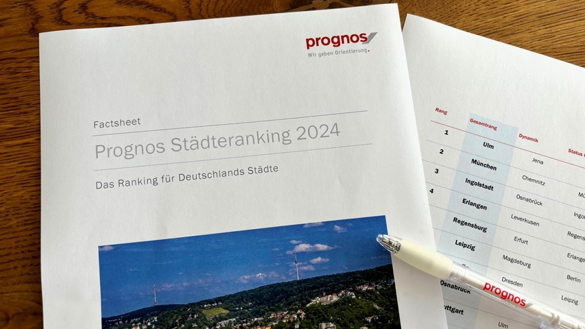Zwei Seiten des Prognos Städteranking 2024 liegen auf einem Tisch, darüber ein Prognos-Kugelschreiber