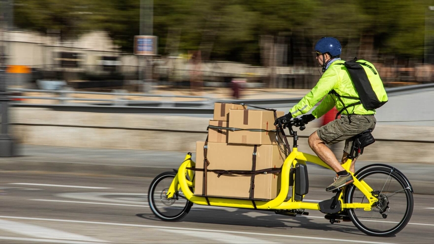Paketzusteller fährt auf einem Elektro-Lastenrad durch die Stadt