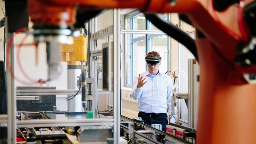 Mann mit VR-Brille gestikuliert vor einer Fertigungsmaschine