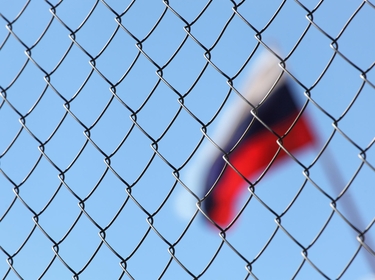 Russische Flagge weht hinter einem Zaun