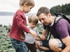 Vater spielt mit Kindern an einem See