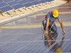 Ein Arbeiter legt Solarpanele auf ein Dach