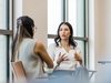 Zwei Frauen sitzen in einem Büro und sprechen miteinander