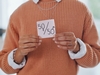 Person mit einem Zettel in den Händen, auf dem 50/50 (Männer und Frauen) steht