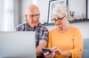 Zwei Senioren benutzen Laptop und Smartphone