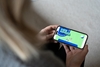 Eine Person schaut über ein Smartphone auf die Webseite von UseTheNews