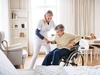Pflegefachkraft, die einer Seniorin aus dem Rollstuhl hilft