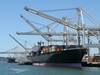 Ein großes Containerschiff wird von Kränen im Hafen mit Containern beladen.