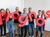 Prognos Mitarbeitende halten rote Buchstaben mit dem neuen Prognos Logo in der Hand