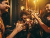 Menschen lachen ausgelassen in einer Bar und stoßen an